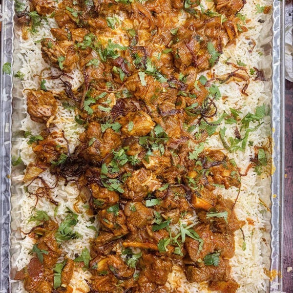 Desi Daawat's chicken biryani, a flavorful Indian dish with rice, chicken, fried onions, and cilantro.