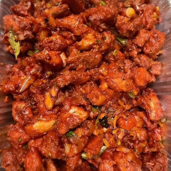 Close-up of Desi Daawat's Chicken 65, featuring crispy red chicken pieces with spices and curry leaves.